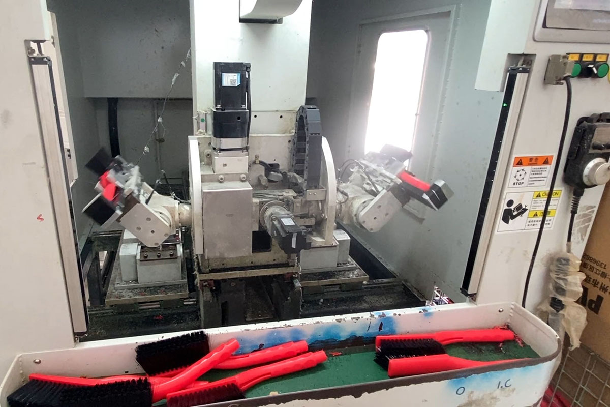Interior view of CNC bristle cutting machine showing precision robotic trimming mechanism