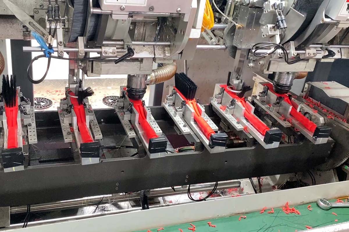 Close-up of tufting machine mold stations with red bristle bundles being inserted